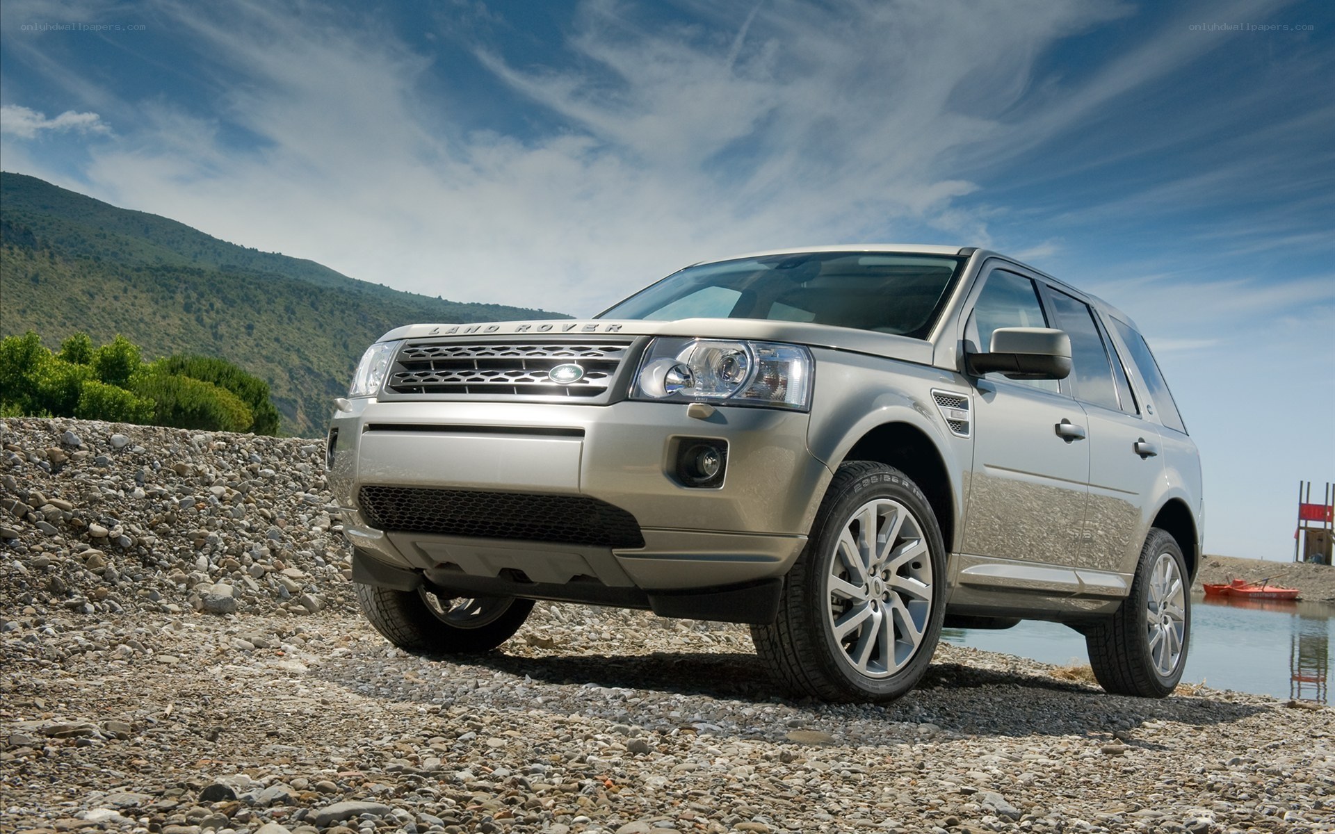 Silver Land Rover on a pebble beach