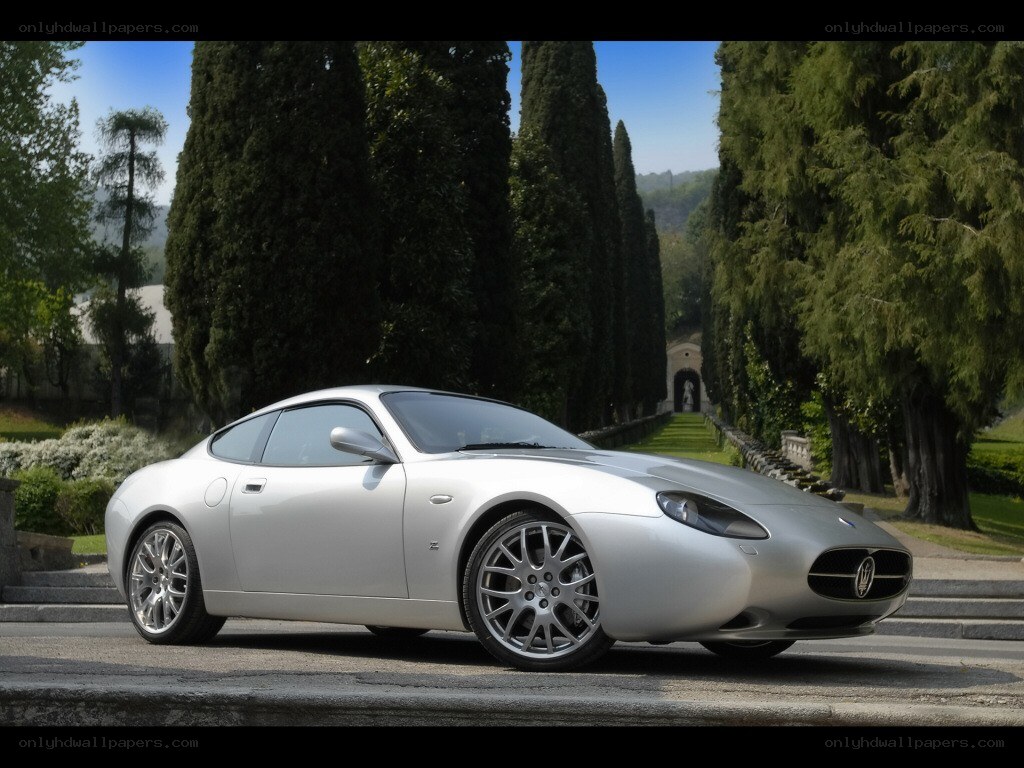 Silver Maserati on a tree-lined road