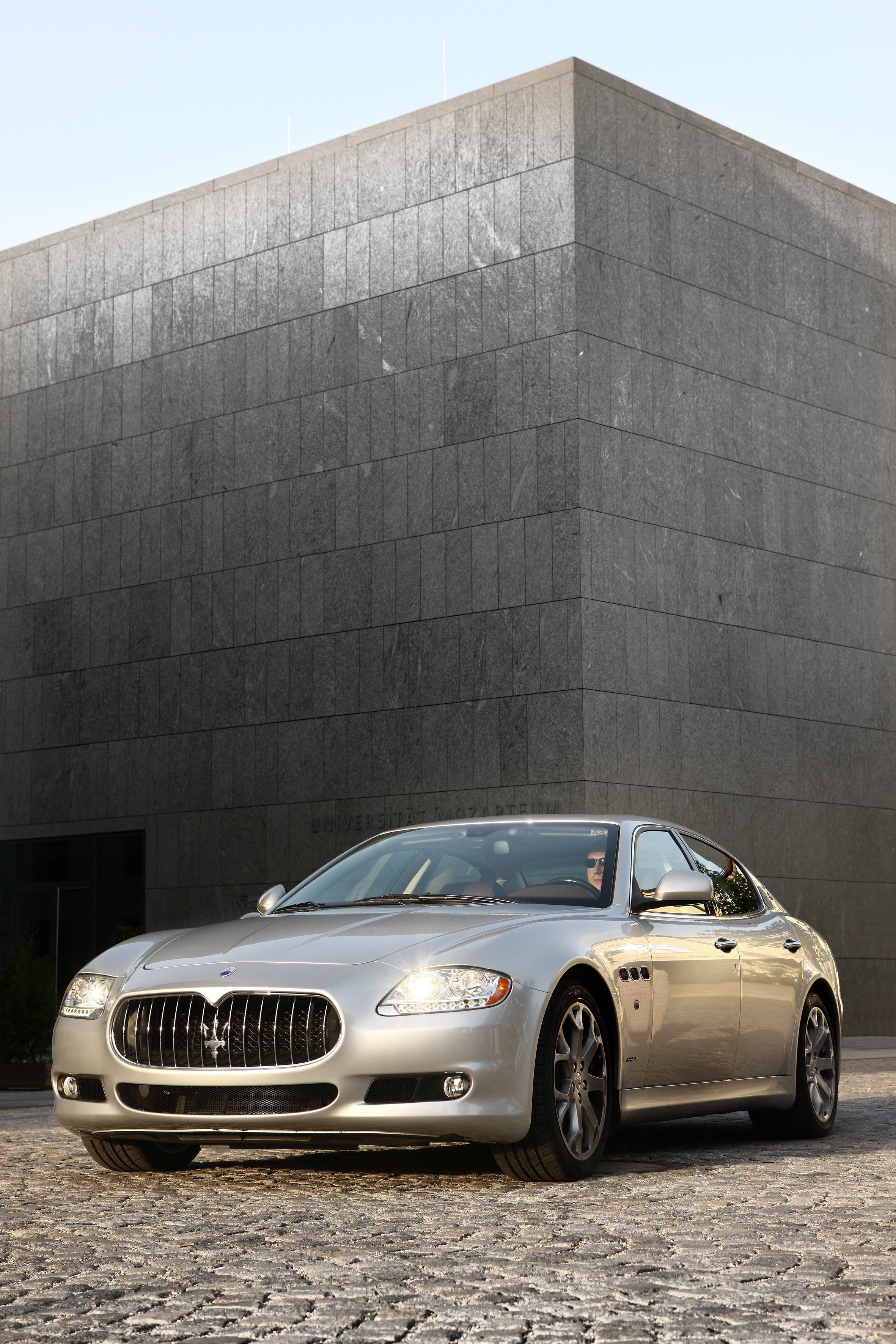 Silver Maserati parked outside building