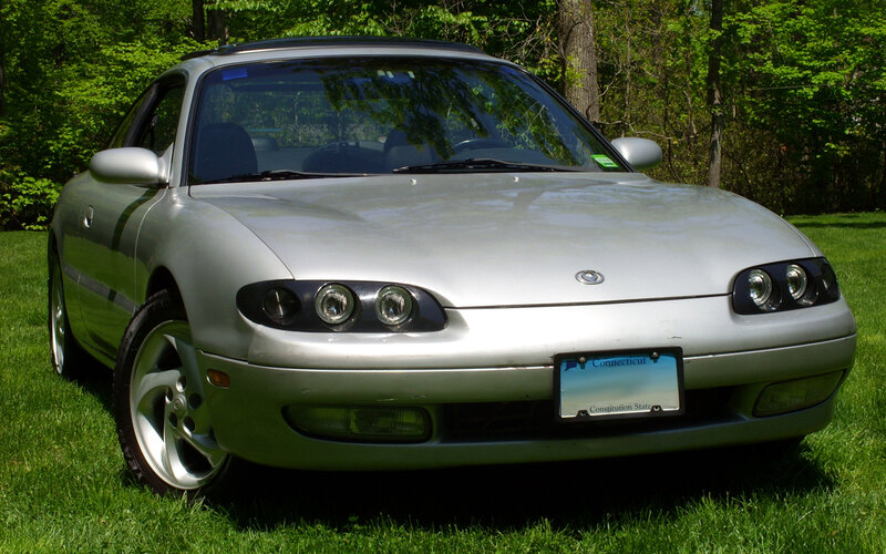 silver mazda miata parked in grass