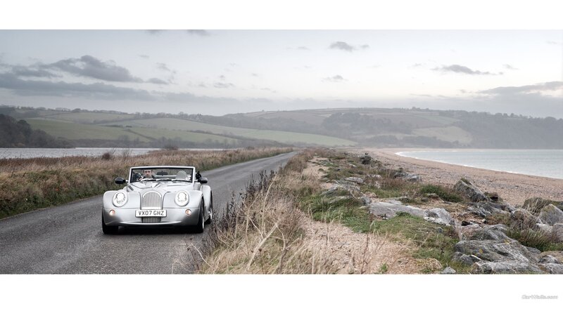 Silver Morgan car on coastal road