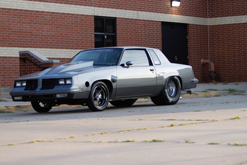 Silver Muscle Car — Gray, Dramatic, Afternoon, Photograph, Brick Building