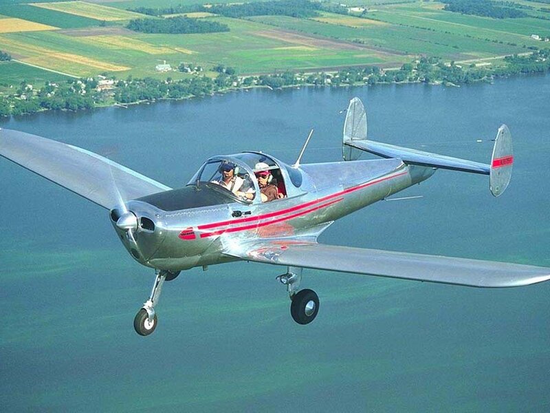 Silver plane flying over lake