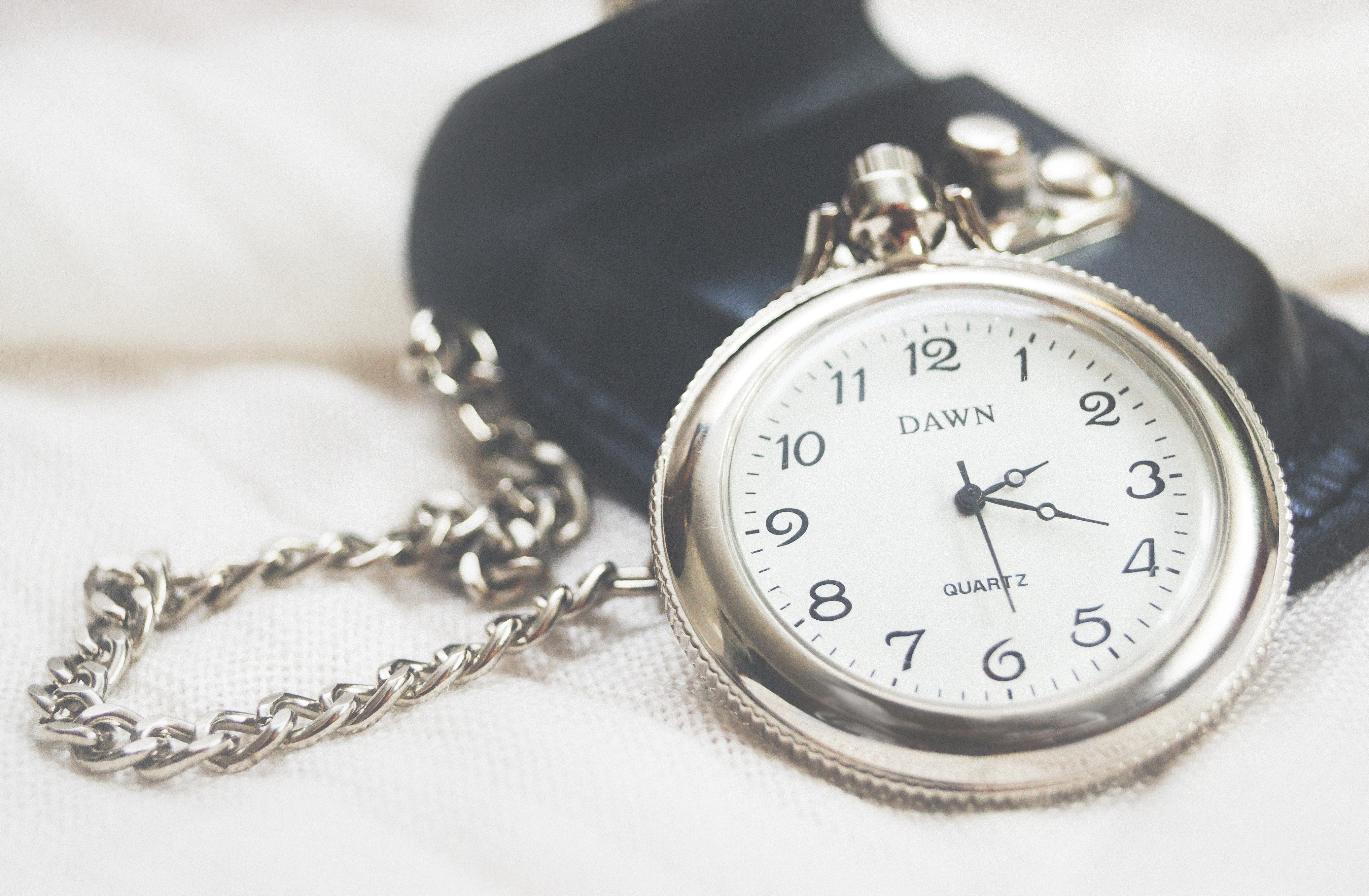 silver pocket watch on fabric