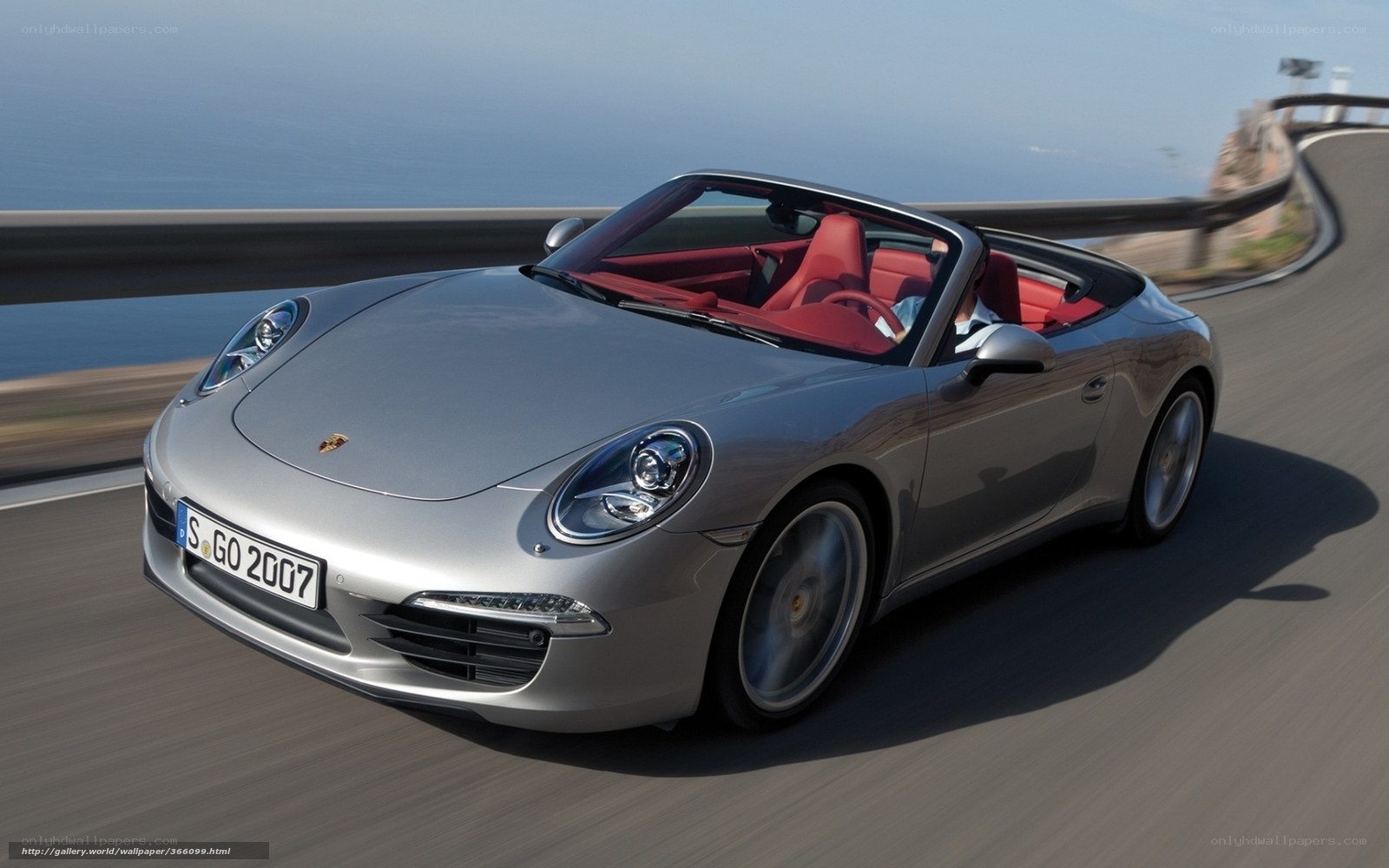 Silver Porsche 911 driving on coastal road