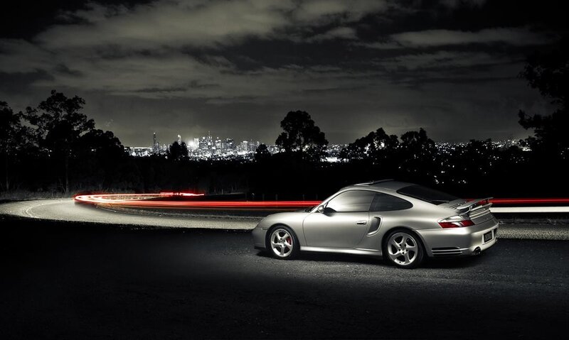 Silver Porsche at night with city lights