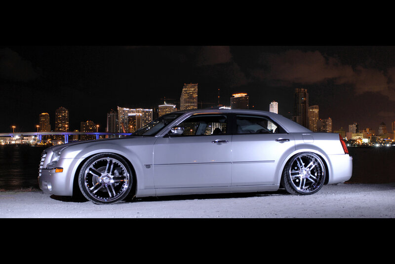 silver sedan at night with city skyline