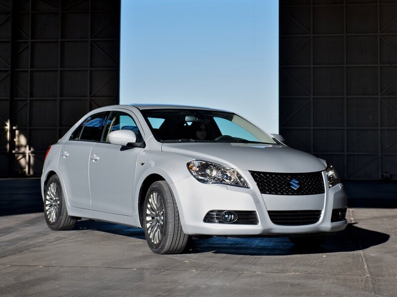 silver sedan in front of hangar