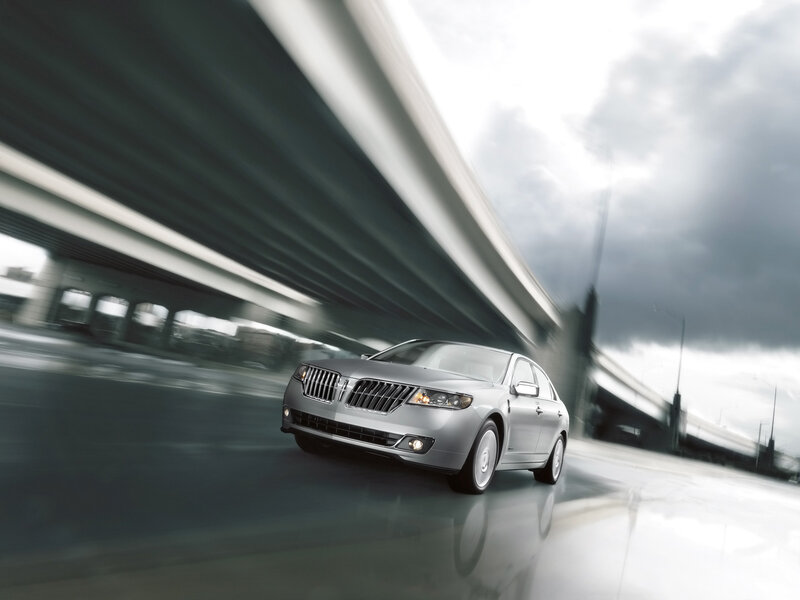 Silver sedan on highway under overpass