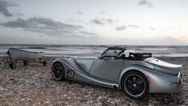 Silver sports car on a pebble beach