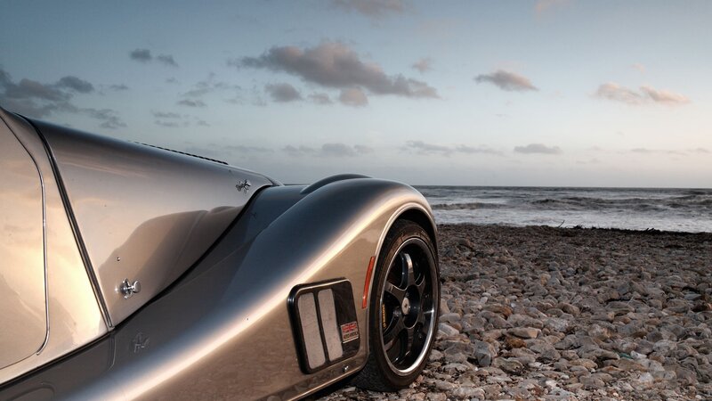 Silver sports car on a pebble beach