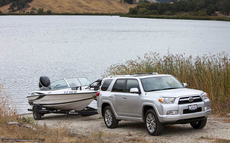 Silver SUV towing boat at lake