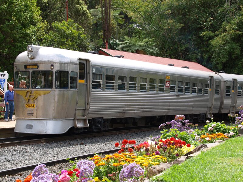 Silver train at a flower-lined station