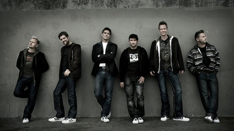 six men posing against a wall