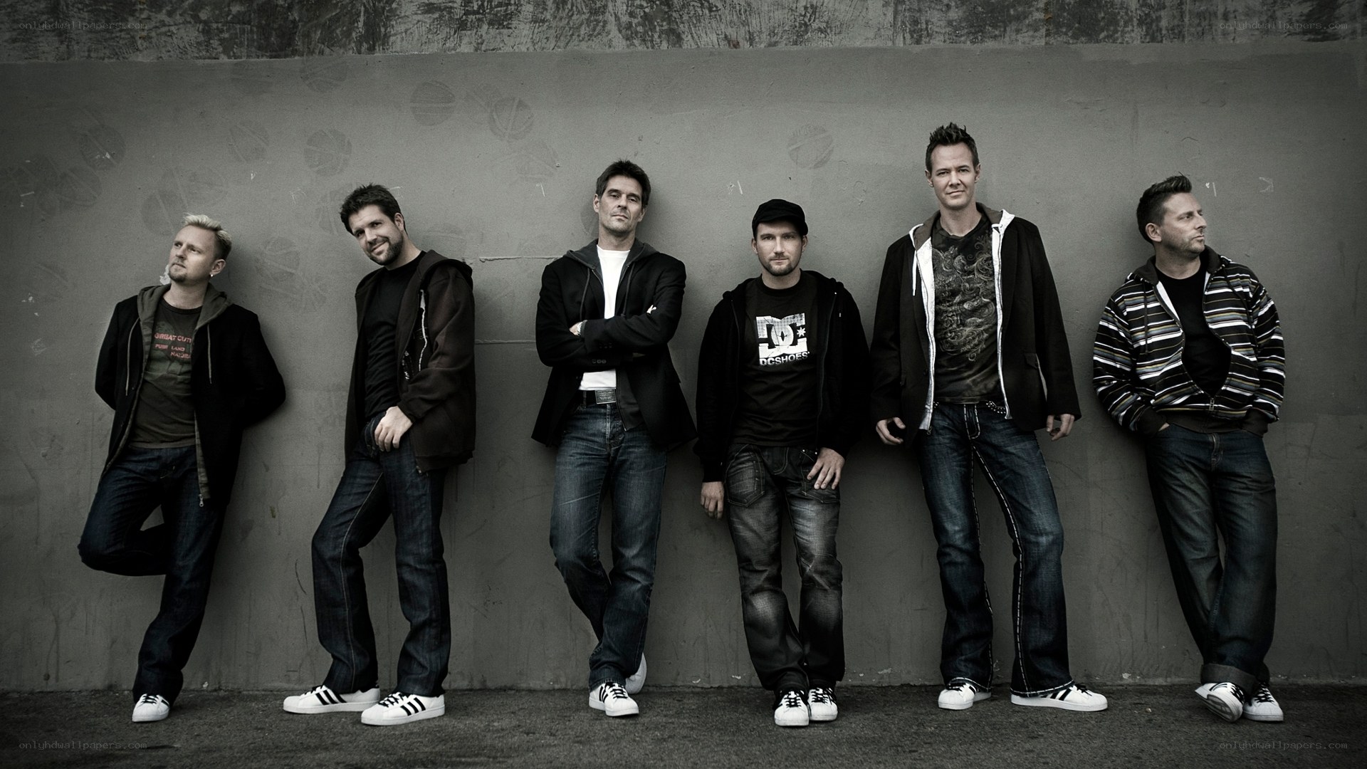 six men posing against a wall