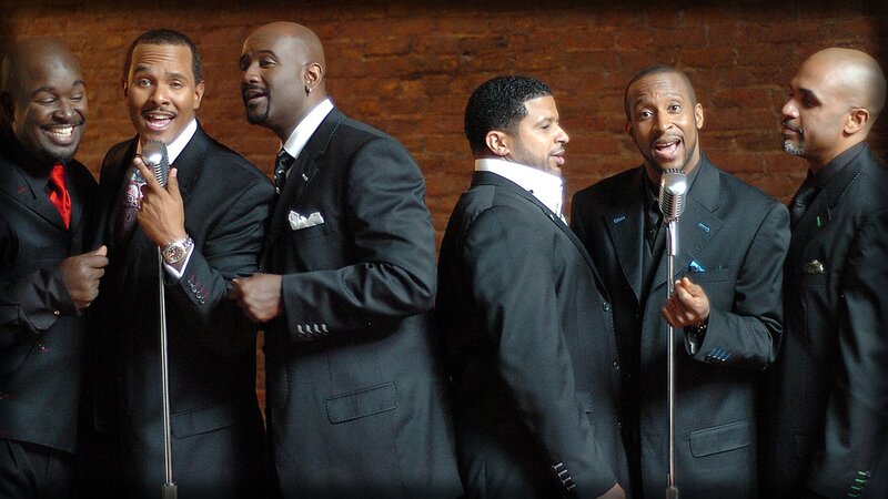 six men singing in suits