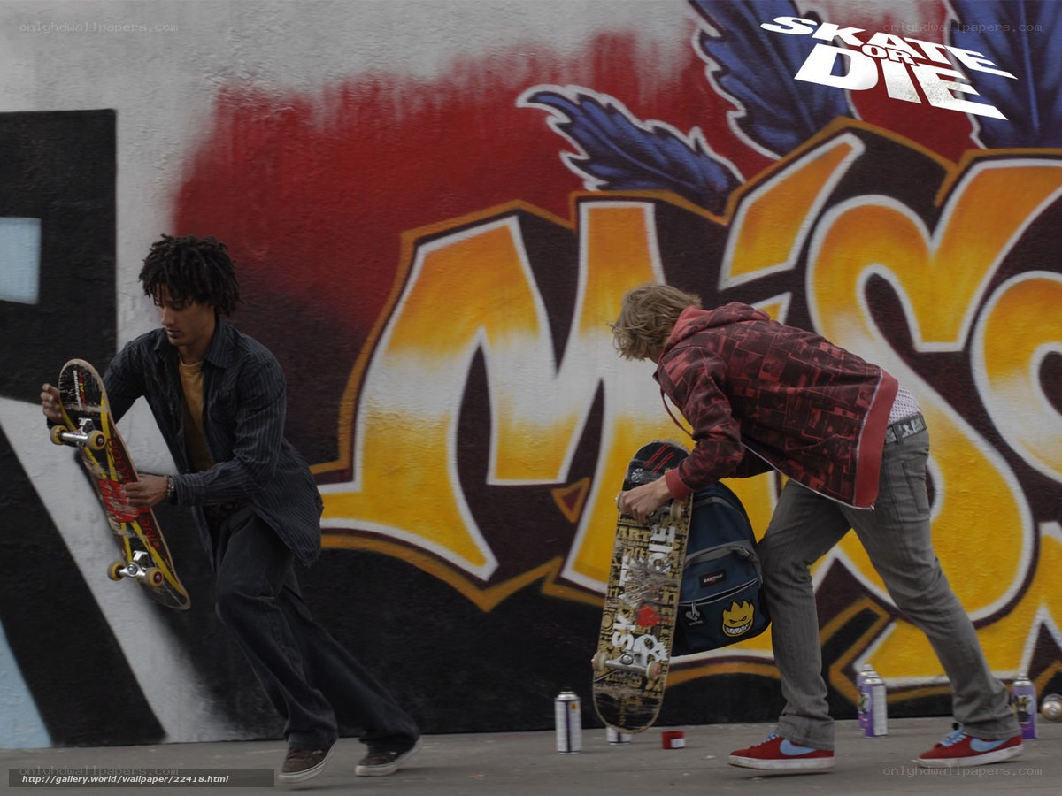 Skateboarders near graffiti wall