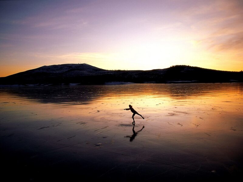 Skater on frozen lake at sunset