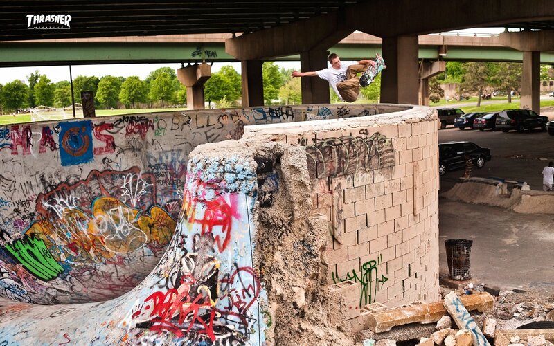 Skater performing trick under bridge