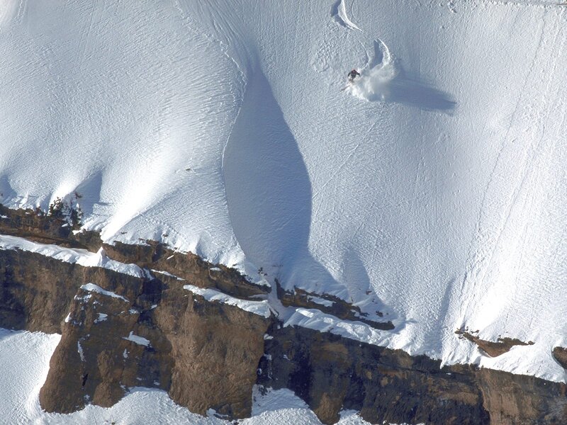 Skier descending snowy cliff
