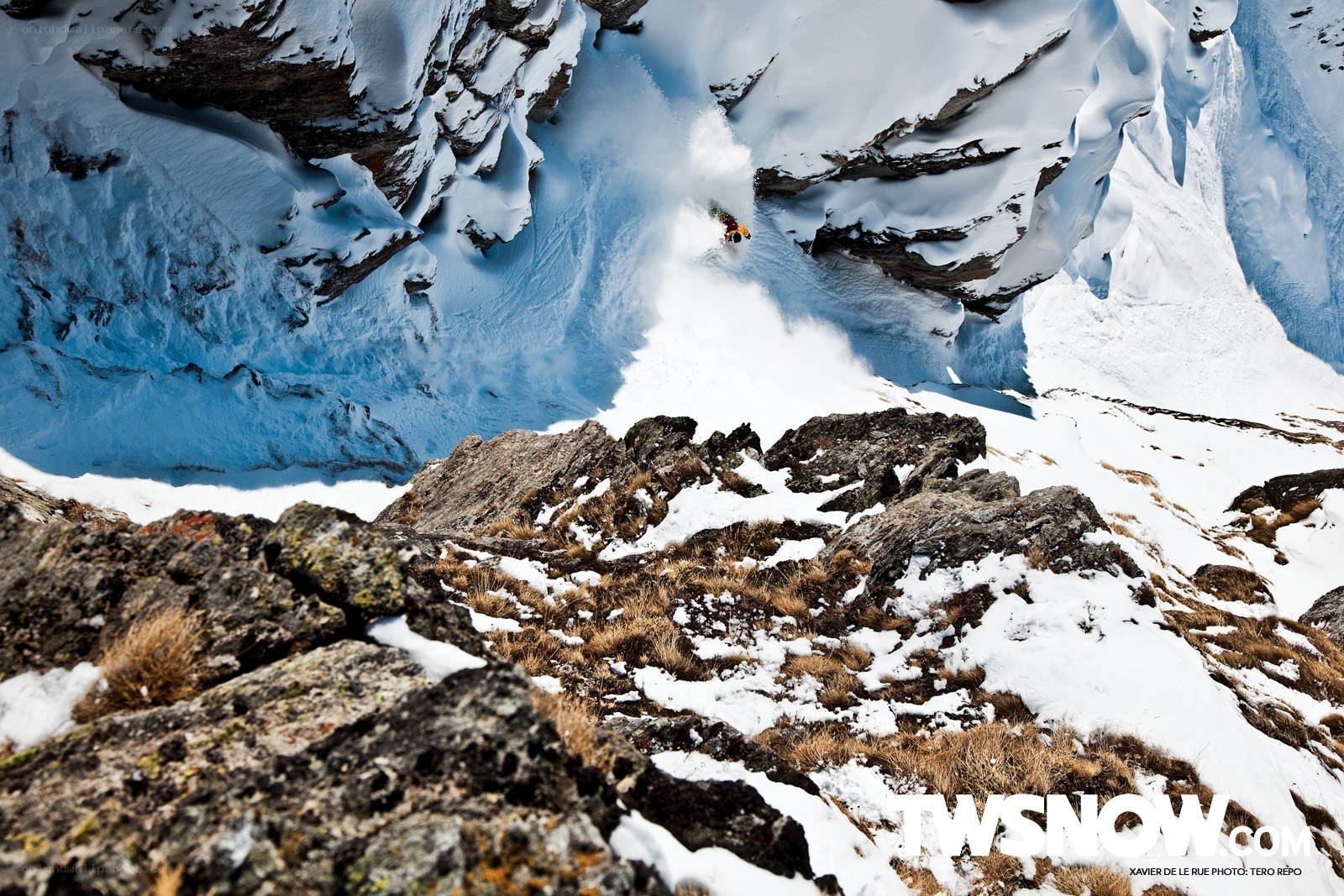 Skier descending snowy cliff