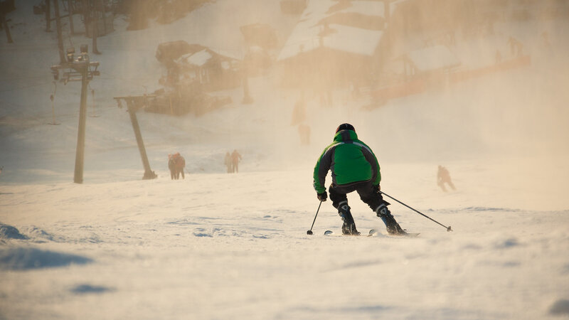 Skier in Green Jacket — White, Dramatic