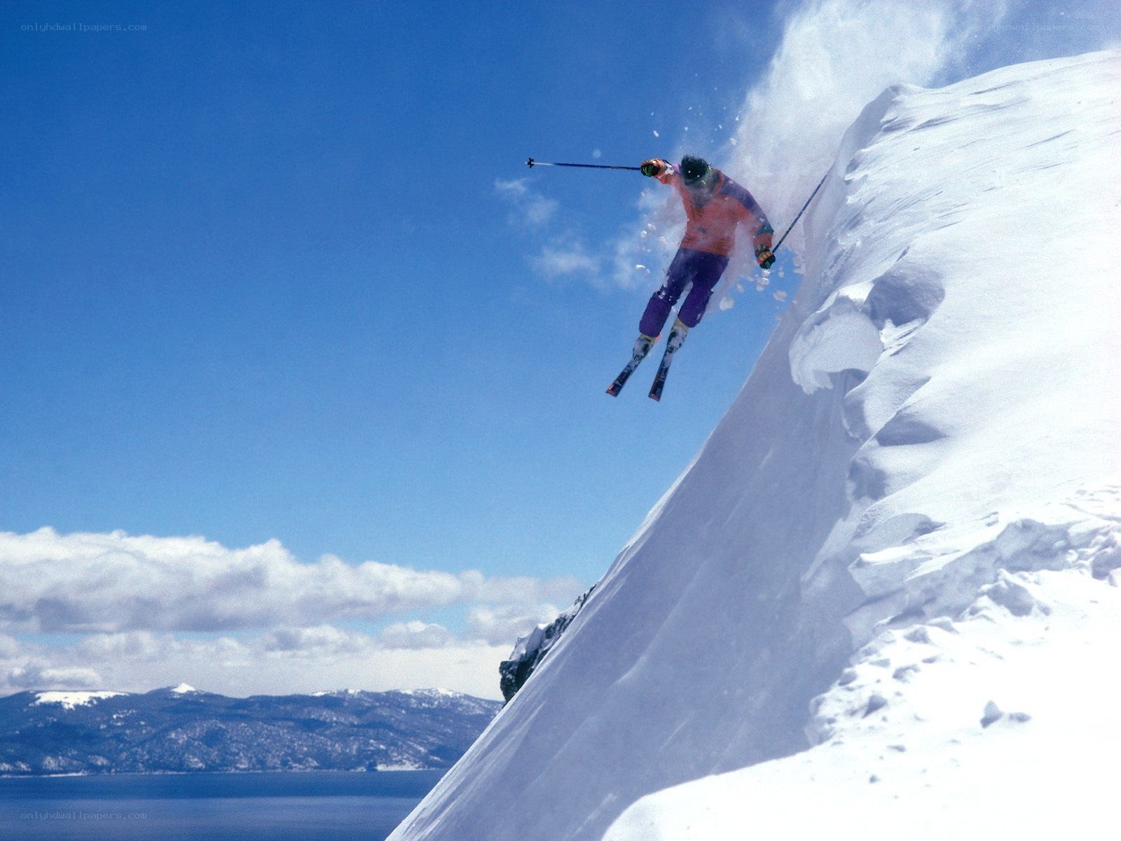 Skier jumping off snowy cliff