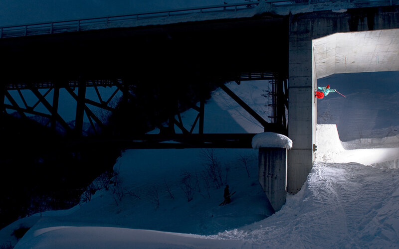 Skier jumping under a bridge