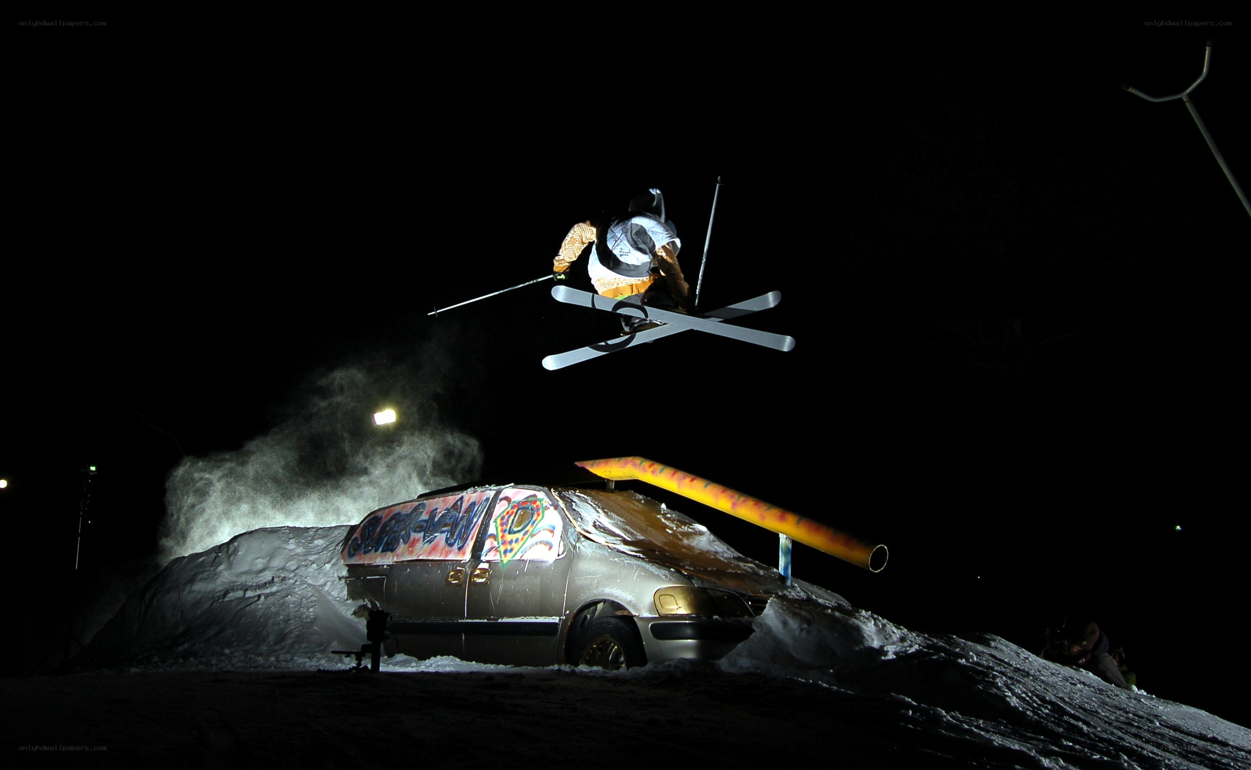 Skier jumps over van at night
