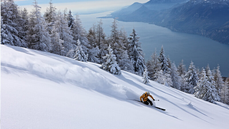 Skier on snowy slope by lake