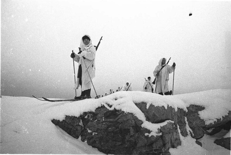 Skiers with rifles on snowy mountain