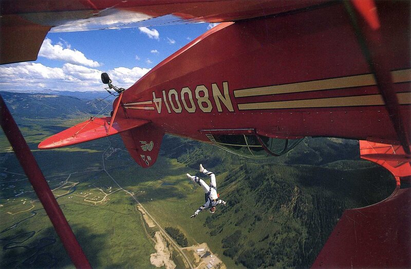 Skydiver exiting red biplane