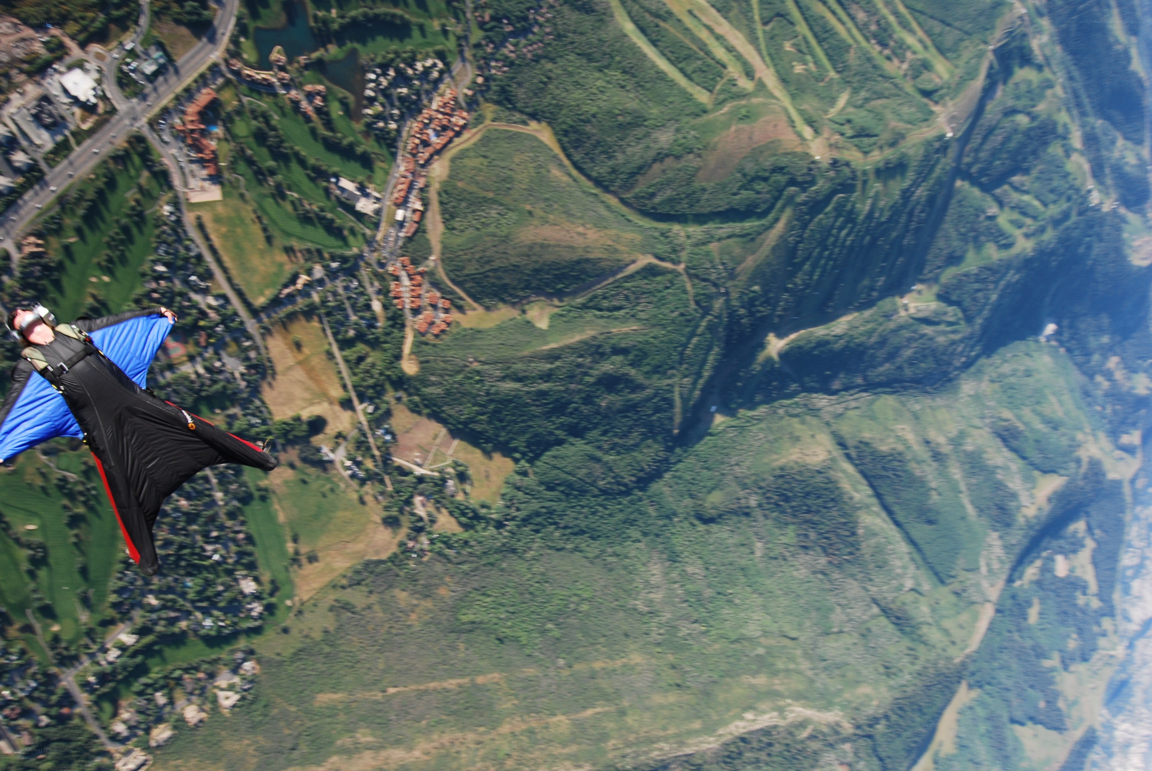 Skydiver over green hills