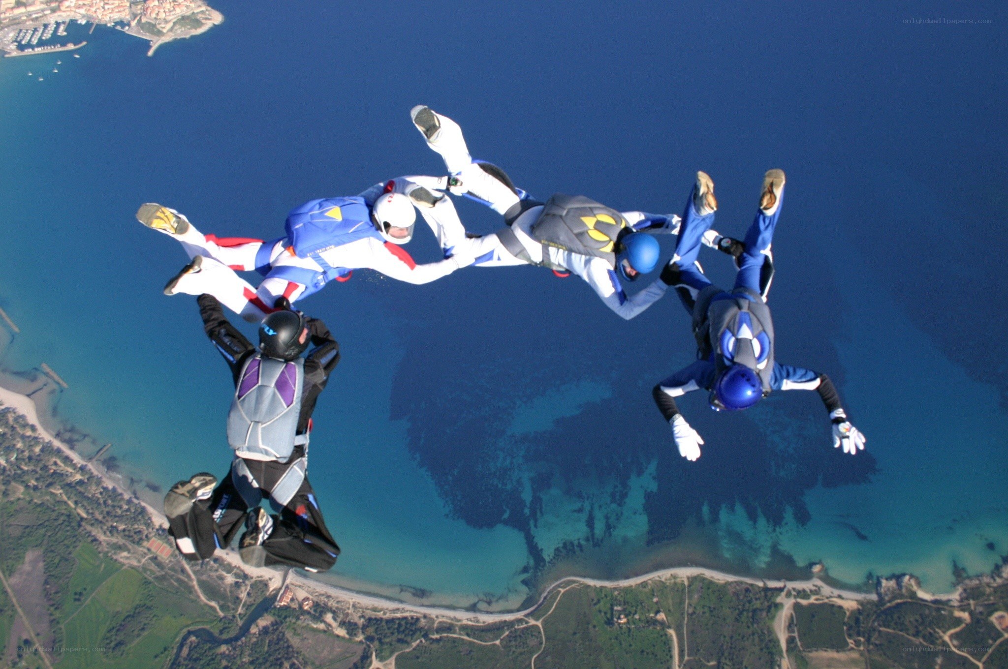Skydivers in formation over coastline