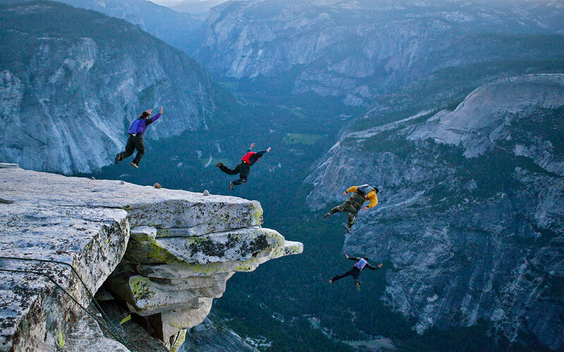 Skydivers leaping from a cliff