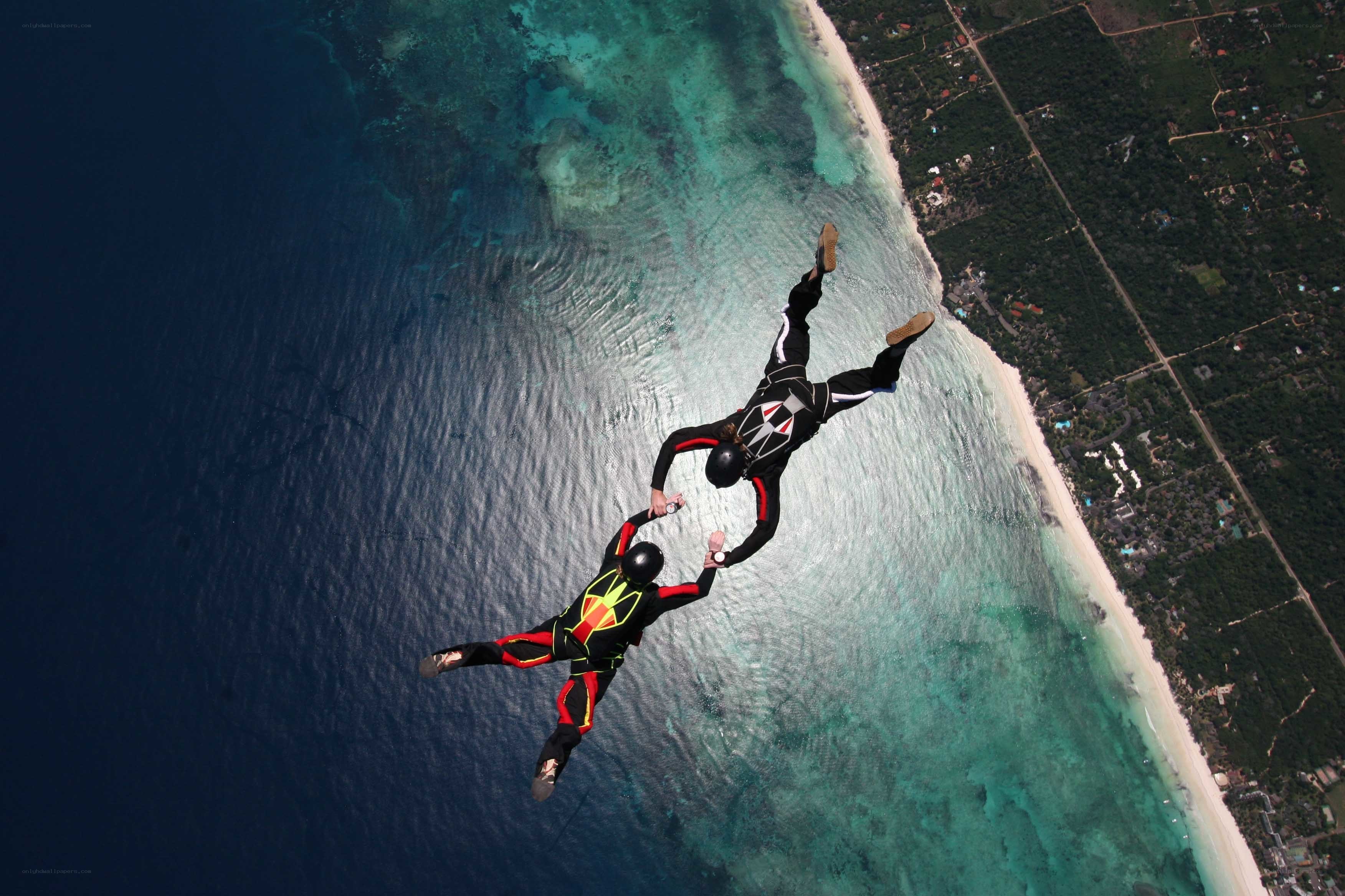 Skydivers over tropical coast