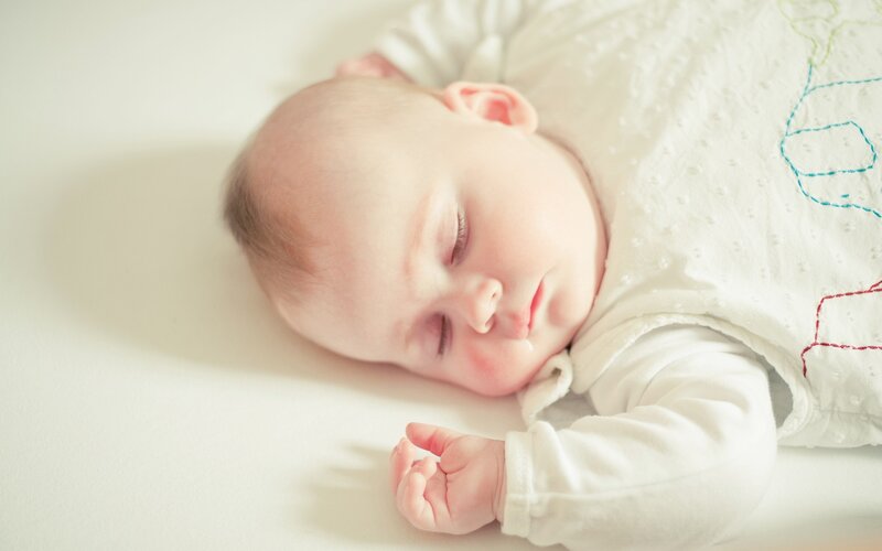 sleeping baby in white onesie