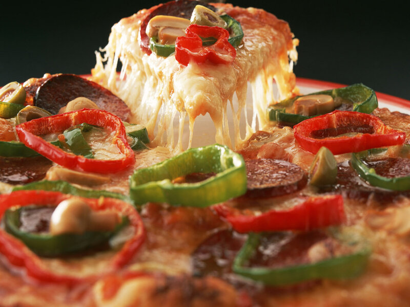 Slice of cheesy pizza with vegetables