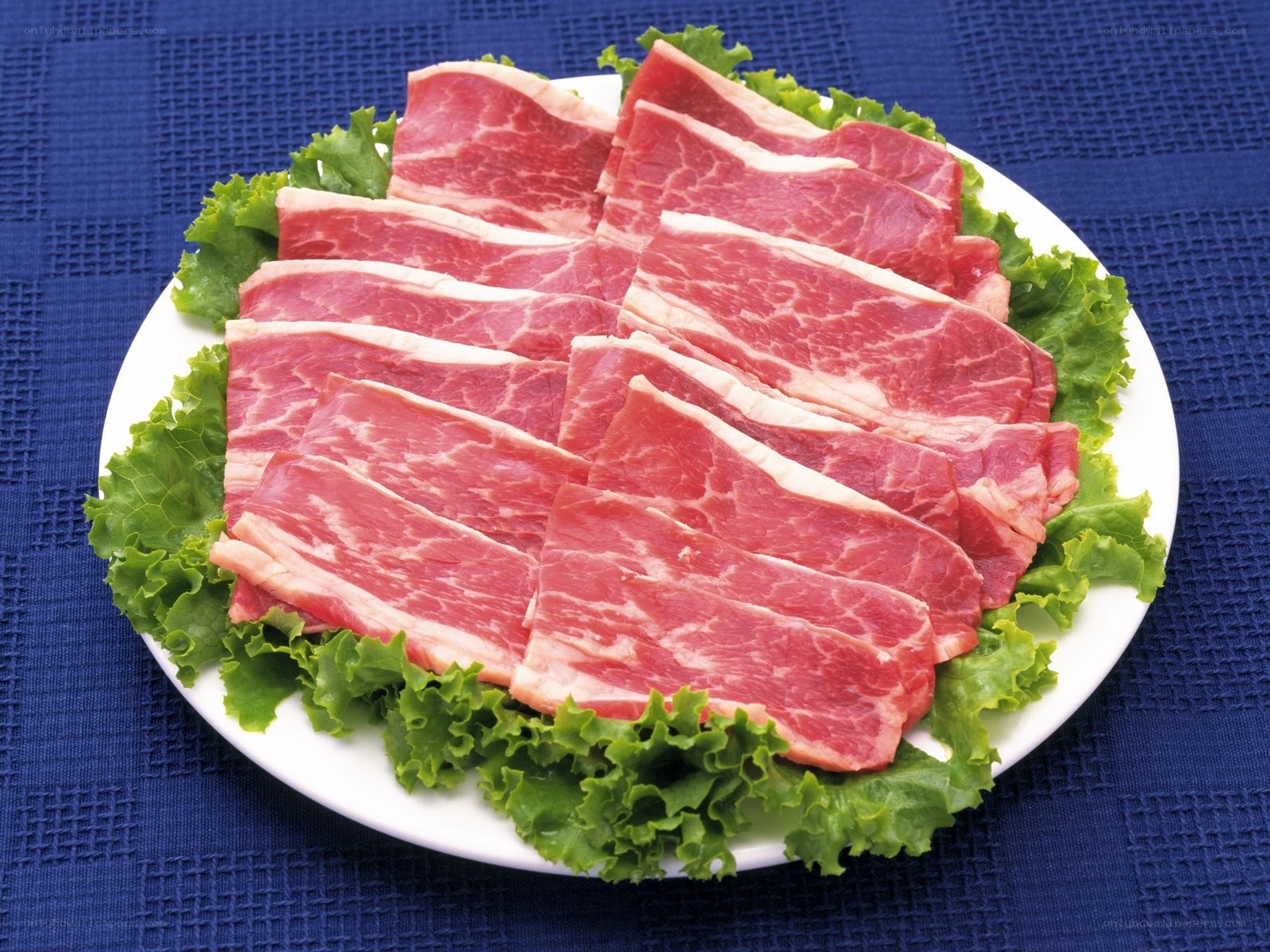 Sliced raw beef on lettuce