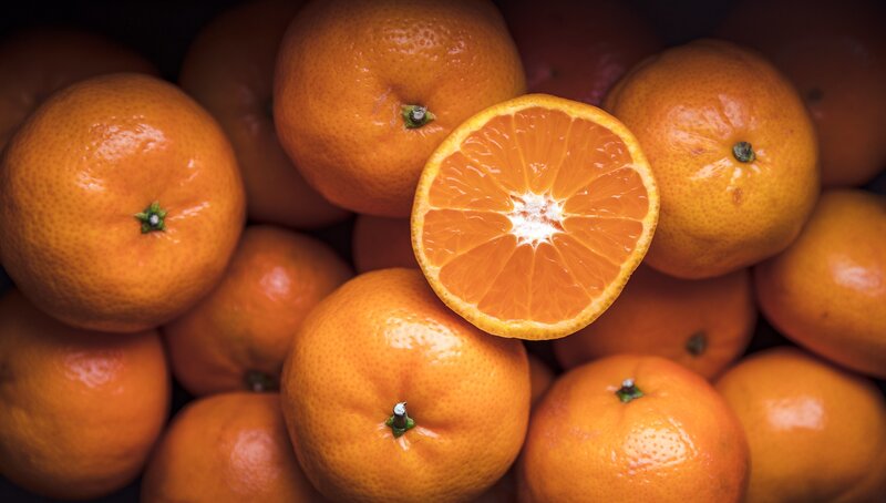 Sliced Tangerine Among Whole Ones