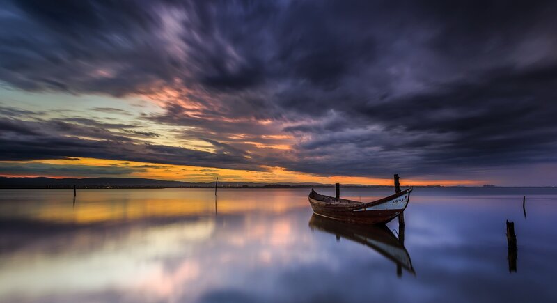 Small Boat at Sunset — Blue, Dramatic, Photograph, Sky, Water, Mountains