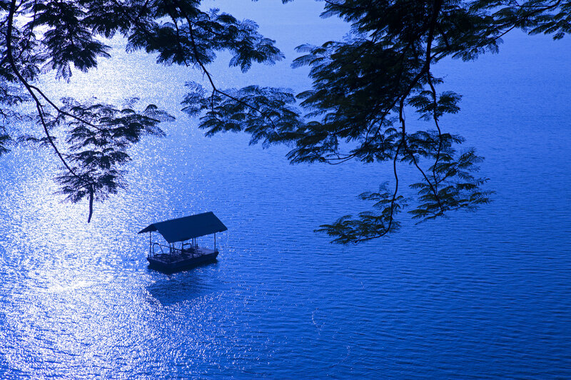 Small Boat on Water — Blue, Serene, Sunset, Photograph, Tree Branches