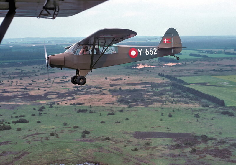 Small plane flying over green fields