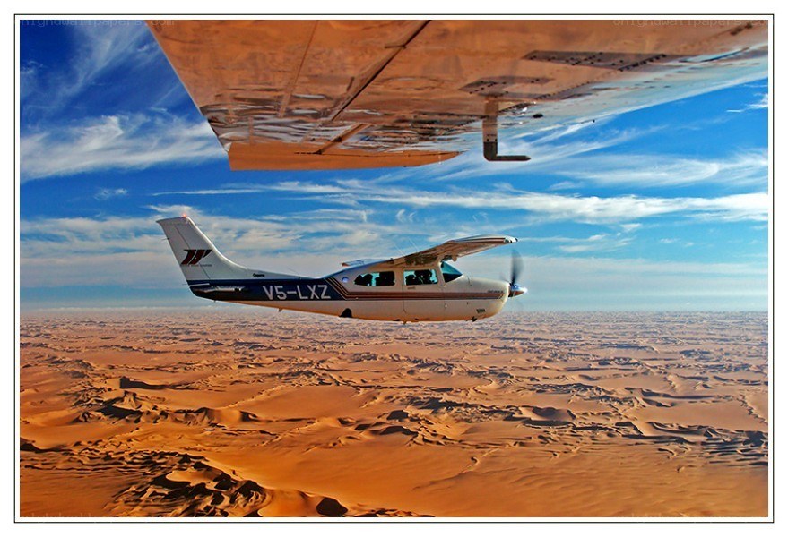 Small plane over desert dunes