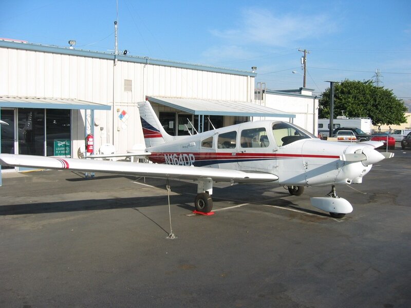 small white airplane parked outside hangar