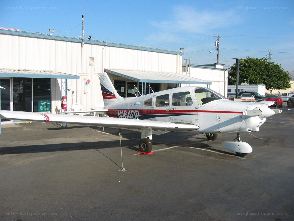 small white airplane parked outside hangar