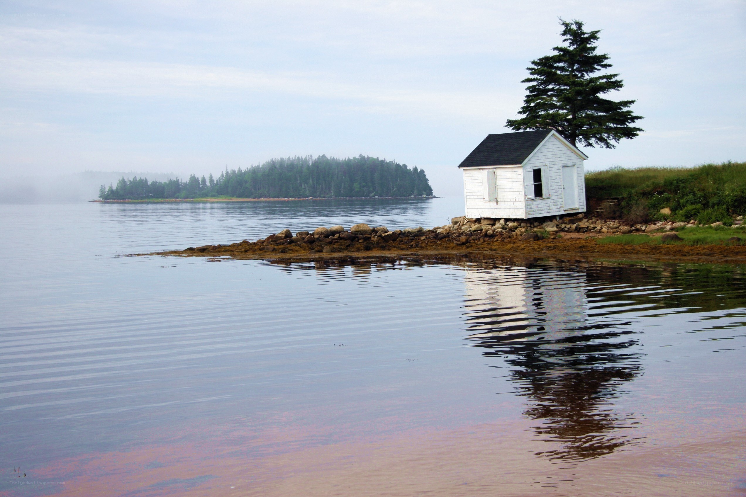 Small white cabin on a rocky shore