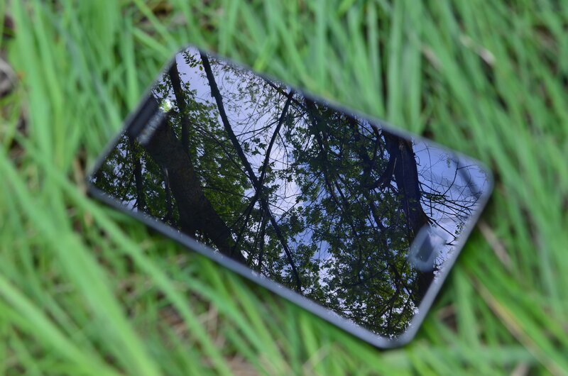 smartphone on grass reflecting trees