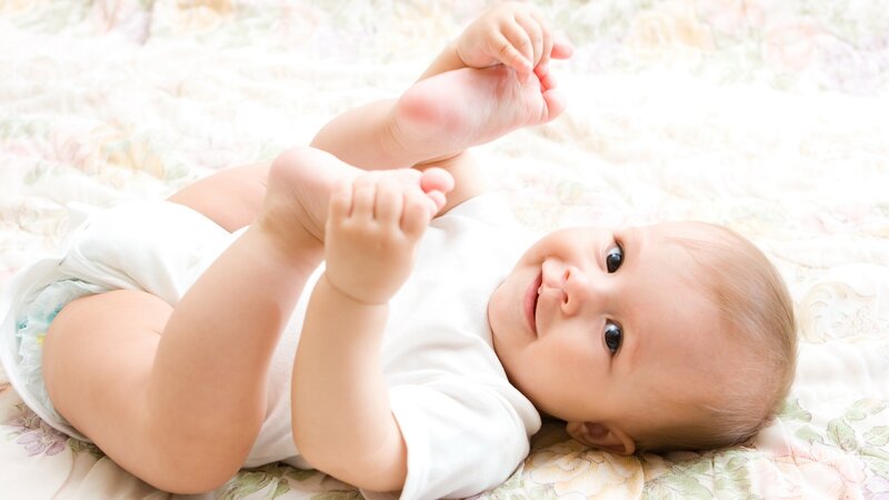 smiling baby lying on bed