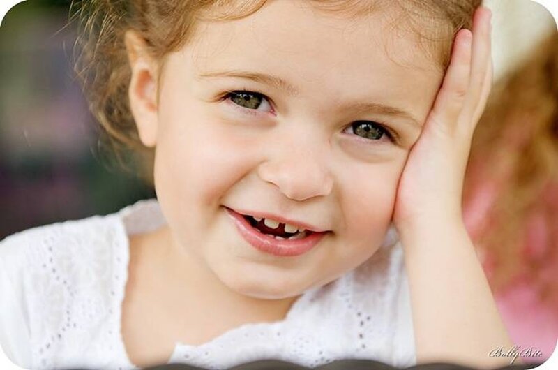 smiling young girl with hand on cheek